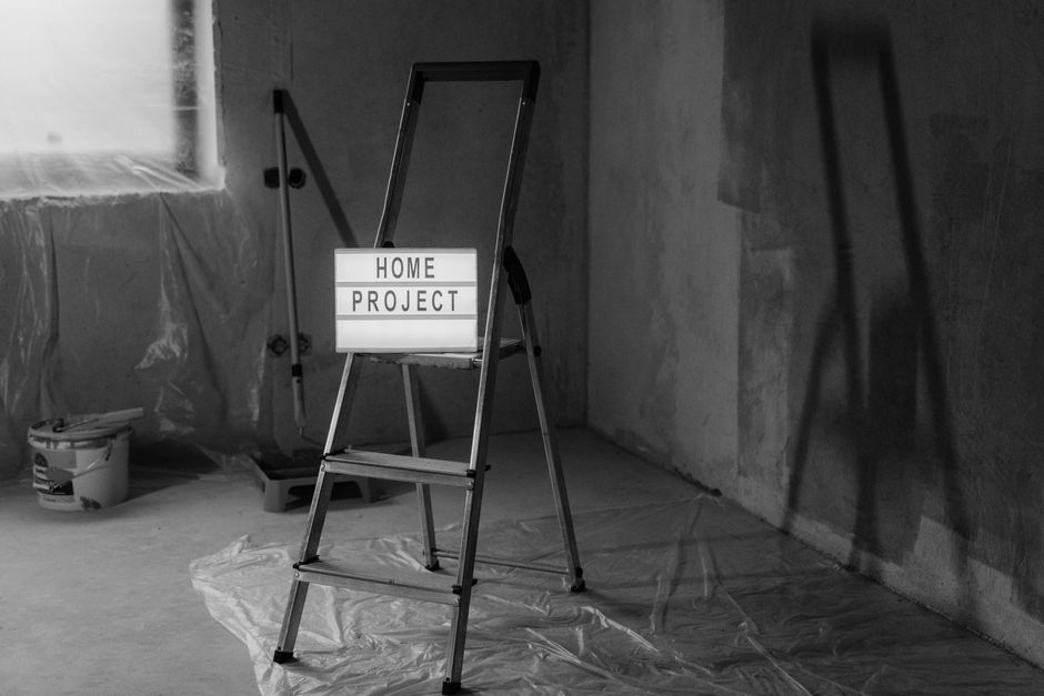 Black and white image of a step ladder with a 'home project' sign in a renovation setting.